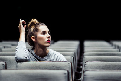 Young woman sitting in stadium at night