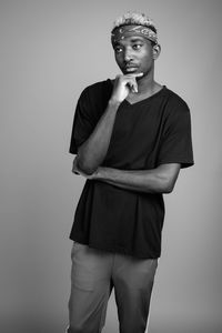 Young man standing against gray background