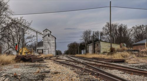 Railroad tracks by bare trees against sky