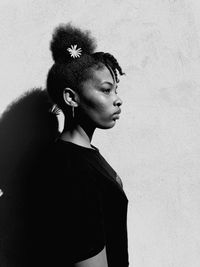 Young woman looking away against wall