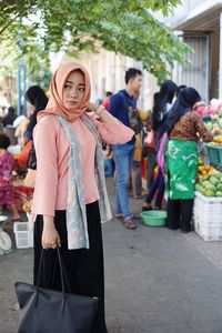 Young woman wearing hijab while looking away on street in market