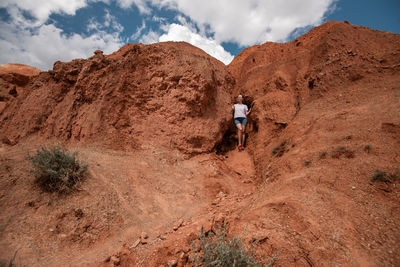 Full length of boy on rock against sky