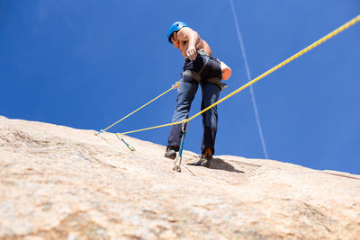 Rear view of shirtless man climbing rock