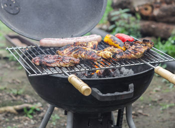 Chicken legs, sausages and peppers on the grill.