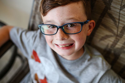 High angle portrait of smiling boy wearing eyeglasses at home