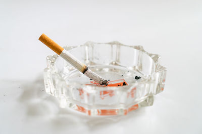 Close-up of cigarette smoking over white background