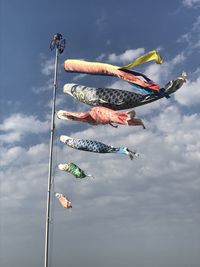 Low angle view of men paragliding against sky