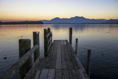 Wooden pier over lake against sky during sunset