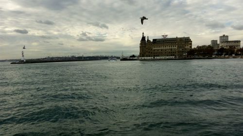 City at waterfront against cloudy sky