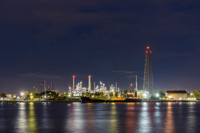 Oil refinery at night petrochemical and energy industry with refection on river