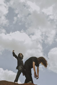 Low angle view of woman with arms raised against sky