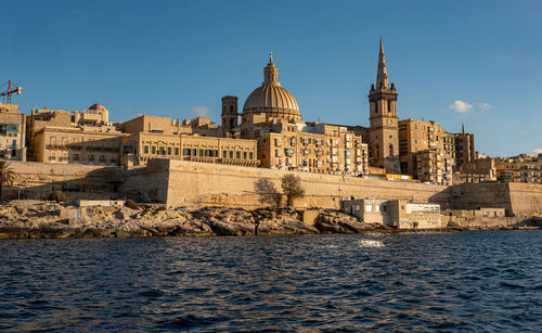 Historic building by sea against sky in city