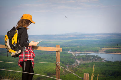 Side view of backpack woman using digital tablet at observation point