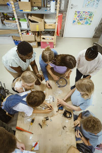 High angle view of male and female pupils working on robotics project with teacher in classroom at school