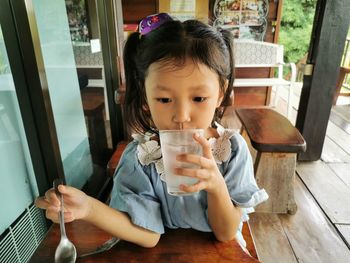 Portrait of cute girl drinking glass on table