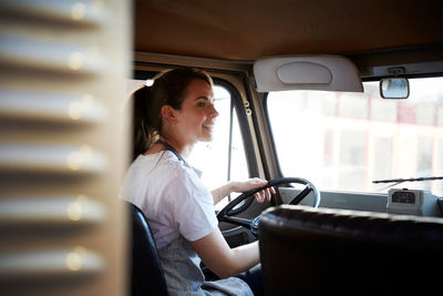 Young female owner driving food truck in city