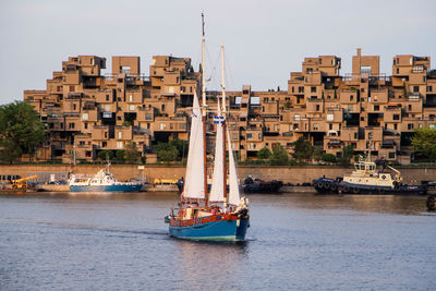 Sailboat sailing on river against city