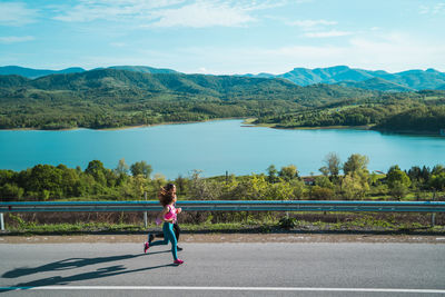 Woman on road by lake against sky