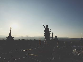 Silhouette statue against sky at sunset