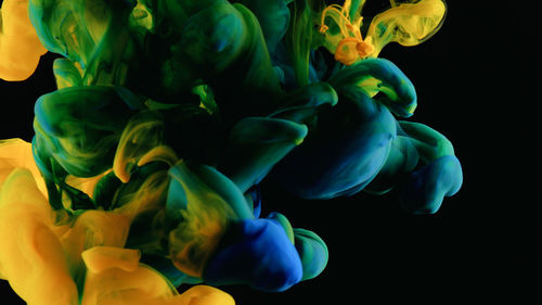 Close-up of blue and yellow liquid over black background
