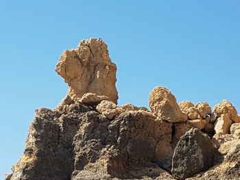 Low angle view of rocks against clear blue sky