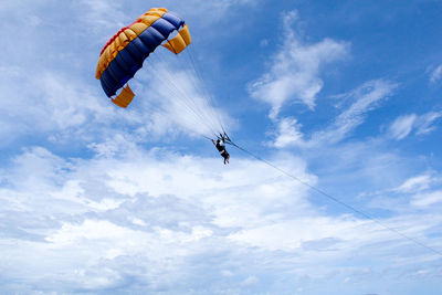 Low angle view of person paragliding against sky