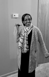 Portrait of smiling woman standing against wall at home