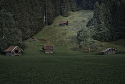 Scenic view of trees and houses on field by mountain