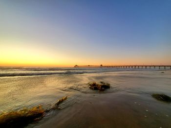 Scenic view of beach against clear sky during sunset