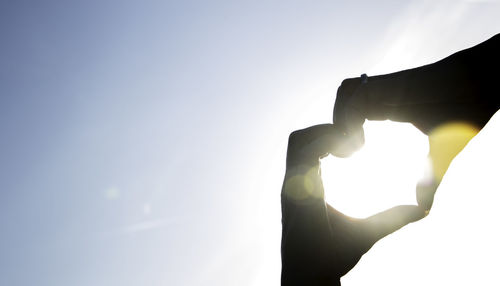 Silhouette man holding sun against sky