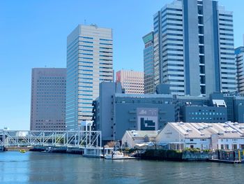 Modern buildings by river against sky in city