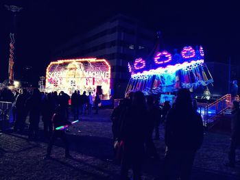 Crowd at illuminated city against sky at night