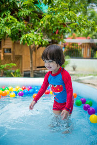 Cute boy playing with ball in swimming pool
