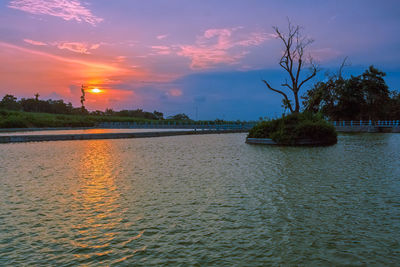 Scenic view of river against sky at sunset