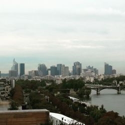 Cityscape by river against sky