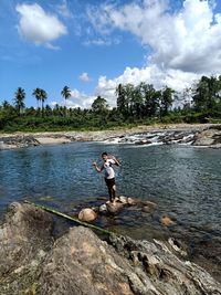 Man on rock by sea against sky