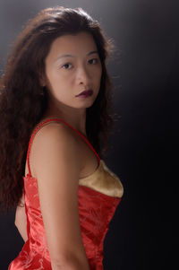 Side view portrait of woman standing against black background