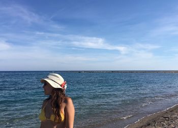 Woman standing at beach against sky