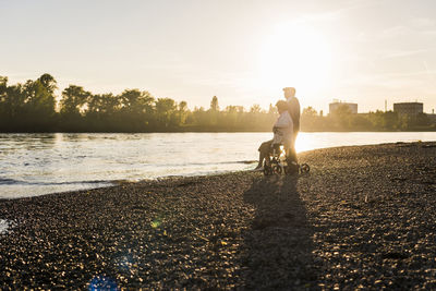 Senior couple with wheeled walker on the beach at sunset