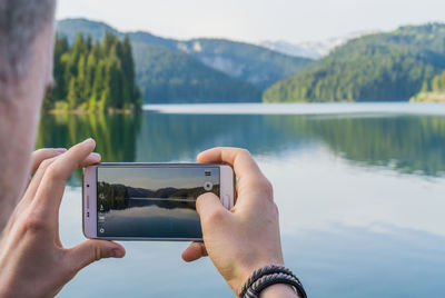 Midsection of man using mobile phone in lake