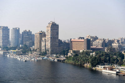 River amidst buildings in city against sky