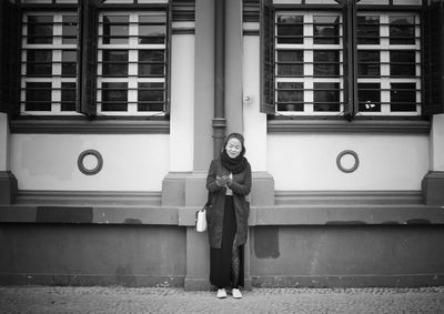 Young woman standing against building