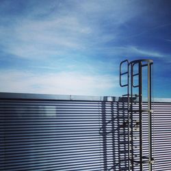 Ladder on building against cloudy sky