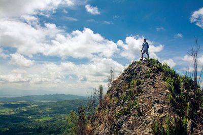 Man standing on rock against sky