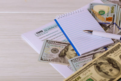 Close-up of pen with blank notepad on currency