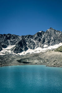 Scenic view of snow covered mountains against clear blue sky