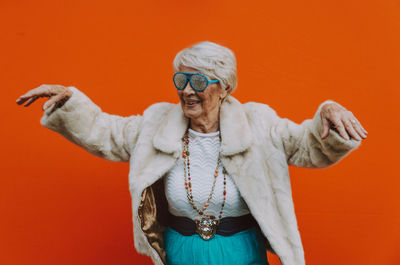 Portrait of smiling woman standing against orange background