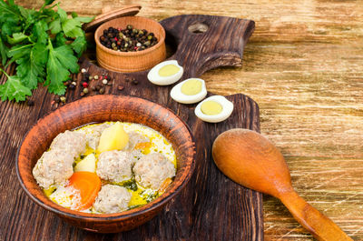 Soup with meatballs and vegetables on a wooden table.