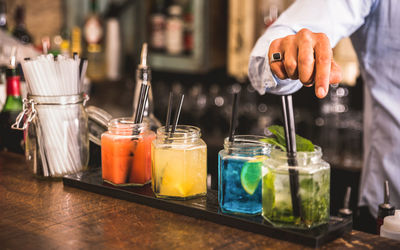 Midsection of bartender with drinks on table standing in restaurant