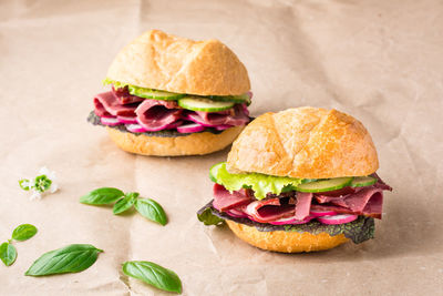 Ready-to-eat hamburgers with pastrami, cucumber, radish and herb on craft paper. american fast food